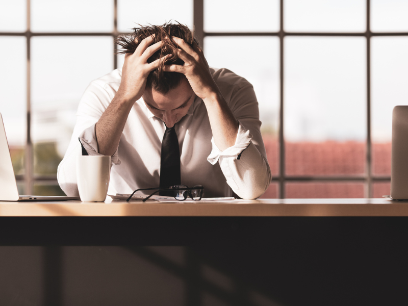 A man with his head in his hand, looking stressed.