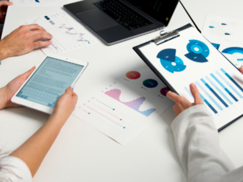 Data analysis meeting: Three people reviewing financial reports and data visualizations.