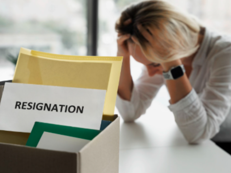 A box containing a resignation letter and other documents, with a stressed person